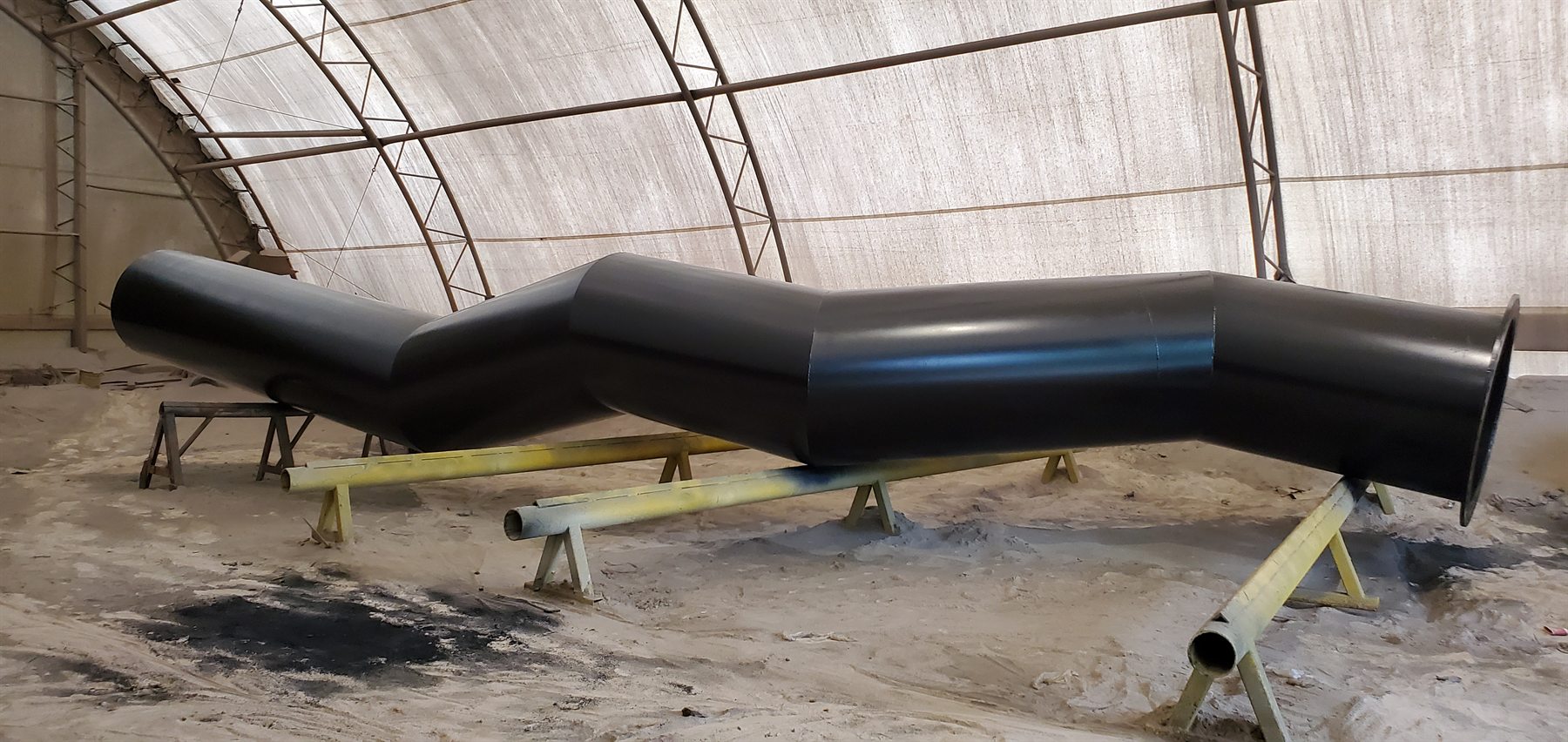 Large black coated ductwork sections in a shop